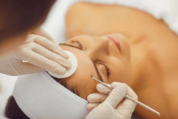 Egy kozmetikus mechanikai tisztítást végez egy nő arcán egy kozmetikai klinikán. Kozmetológus, hogy a bőr tisztítása a fiatal nő a szépségszalonban — Stock Fotó