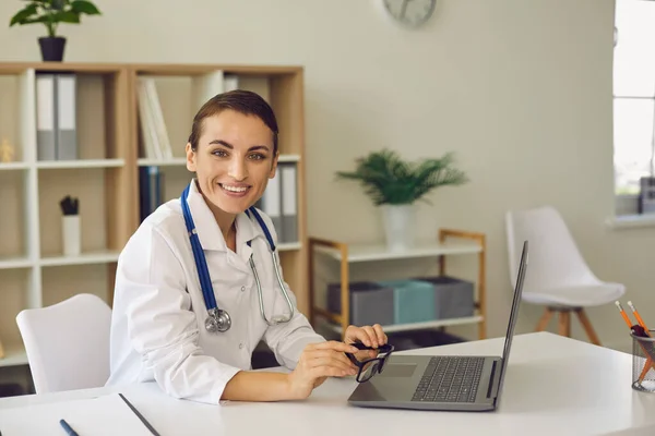 Mulher médico olhando para a câmera durante reunião on-line no laptop — Fotografia de Stock