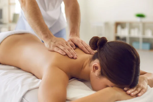 Ansiktslös kvinna ligger på soffan och får en massage av nackkragen området. — Stockfoto