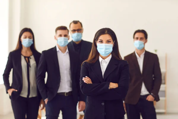 Responsible young company manager with group of workers all wearing face masks at work — Stock Photo, Image