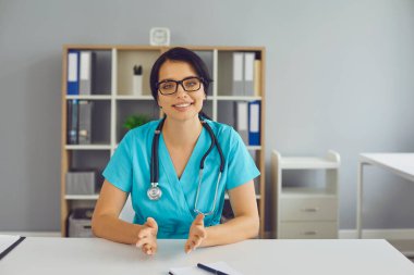 İnternetteki video görüşmesi sırasında genç doktor masada oturup hastaya danışmanlık yapıyor.