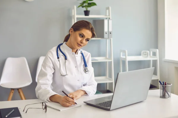 Medico donna che prende appunti durante la lezione online o videochiamata in clinica medica — Foto Stock