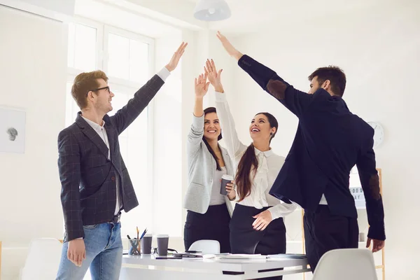 Grupp affärsmän stående leende upp händerna glada står vid ett bord på kontoret. — Stockfoto