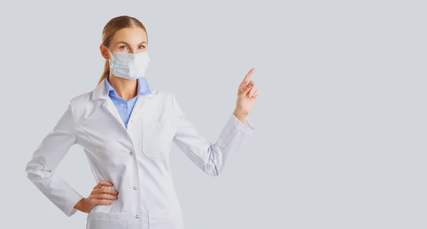 Woman doctor points hand on a gray background — Stock Photo, Image