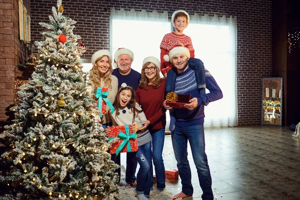 Family in Santas hats decorates the Christmas tree at home on Christmas. — Stock Photo, Image