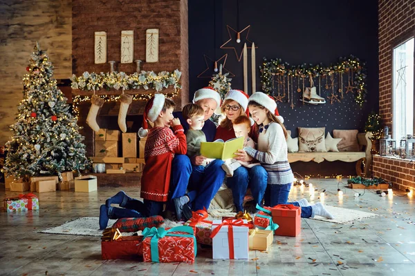 Büyükannem ve büyükbabam Noel günü ağaçlı odada çocuklu bir kitap okuyorlar.. — Stok fotoğraf