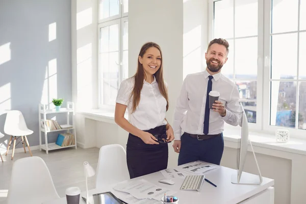 Hombre de negocios positivo y mujer de negocios sonriendo en una oficina blanca. — Foto de Stock