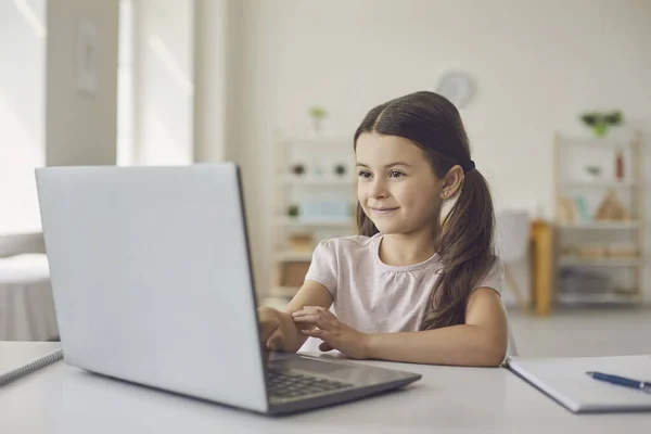 Chica sonriente aprendiendo en línea en el ordenador portátil desde casa —  Fotos de Stock