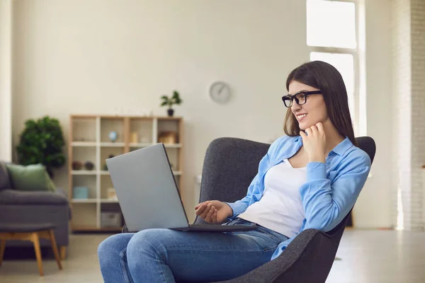 Lächelnde Frau arbeitet online am Laptop und kommuniziert mit jemandem während des Videocalls zu Hause — Stockfoto