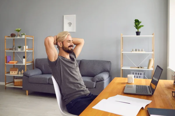 Muž sedí doma, dívá se na monitor notebooku a usmívá se během online setkání — Stock fotografie