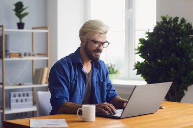 Evden bilgisayarda çalışan genç adam.