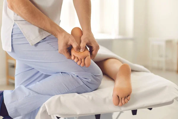 Masajista masculino profesional haciendo masaje de pies para mujer joven en el centro de salud moderno —  Fotos de Stock