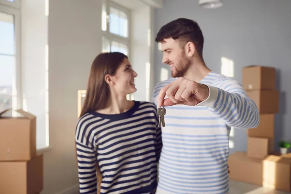 Coppia felice con le chiavi della nuova casa in mano sorridente mentre in piedi in camera. — Foto Stock