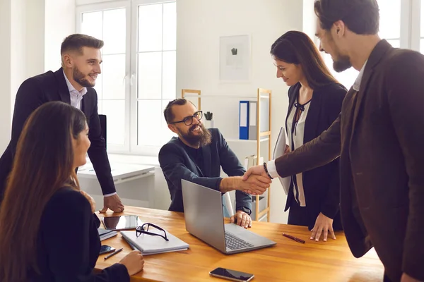 Усміхнені ділові партнери тремтять руками після успішних переговорів з колегами в офісі — стокове фото