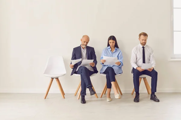 Três candidatos de diferentes idades e etnias sentados em cadeiras à espera de entrevista de emprego — Fotografia de Stock