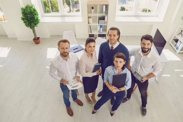 Groupe de gens d'affaires souriants debout avec des documents et regardant la caméra devant — Photo