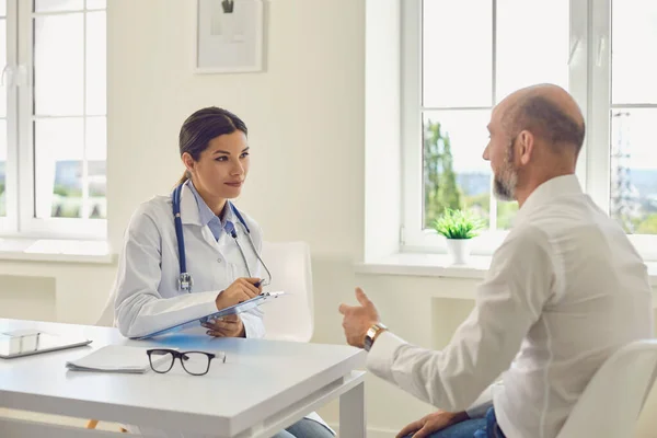 Homme patient pensionné parle avec le médecin au bureau de l'hôpital. — Photo