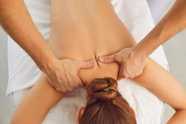 Jovem que gosta de massagem nas costas profissional na clínica de saúde moderna ou centro de spa — Fotografia de Stock