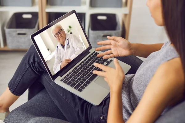 Young woman using laptop and talking to experienced senior doctor during online video consultation — Stock Photo, Image