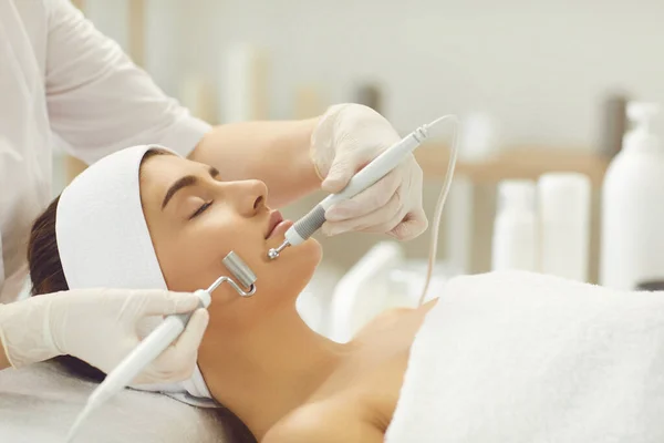 Mujer recibiendo tratamiento de microcorriente facial aparato de terapeuta en salón de belleza — Foto de Stock