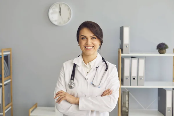 Smiling woman doctor therapist sitting in medical clinic office and looking at camera