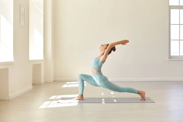 Aktif giyimli güzel bir kadın spor salonunda yoga yaparken Crescent Lunge Asana yapıyor. — Stok fotoğraf