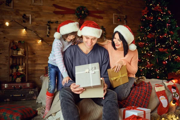 Возбужденные родители с девушкой, открывающей подарки на Рождество — стоковое фото