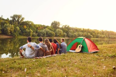 Arkadan bak. Bir grup insan piknikte gülümsüyor.
