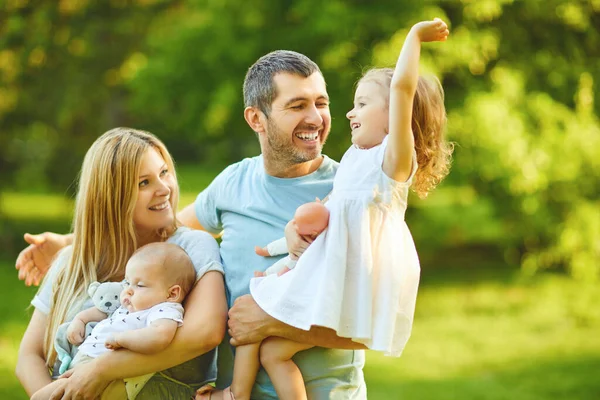 Bebekli bir aile parkta çimlerin üzerinde duruyor. — Stok fotoğraf