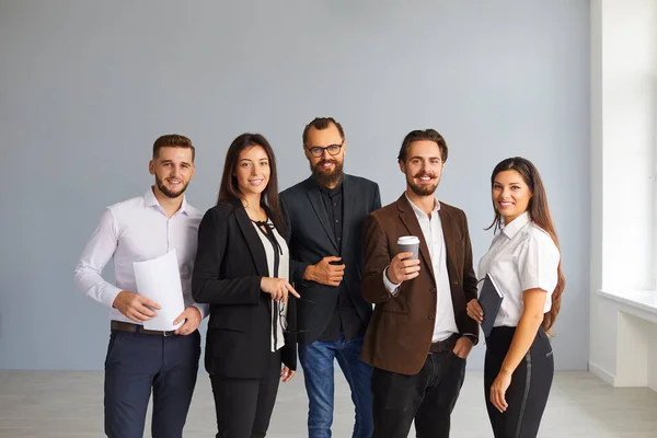 Groupe de jeunes employés de bureau heureux ou startuppers debout ensemble regardant la caméra — Photo