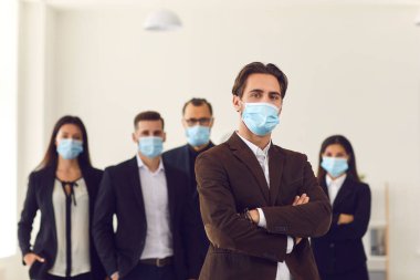 Erkek lider ve sorumluluk sahibi genç şirket çalışanlarının hepsi iş yerinde maske takıyor.