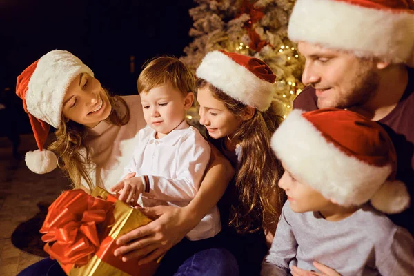 Happy family gives gifts to children in a room at Christmas — Stock Photo, Image