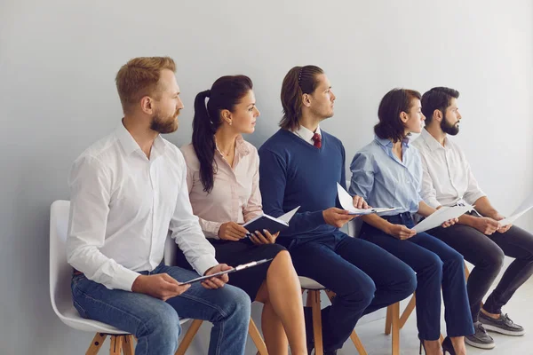 Giovani candidati seduti in fila su sedie in attesa di un colloquio di lavoro nella moderna azienda aziendale — Foto Stock