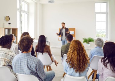 Genç iş adamı toplantı odasında oturan bir grup şirket çalışanının iş projesinden bahsediyor. Çeşitli iş adamları ofiste yapılan bir konferansta şirket büyümesini tartışıyor.