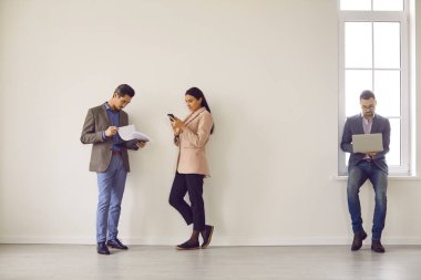 Geniş, aydınlık bir odada, duvarın yanında duran ortakların tam boy fotoğrafı. Bir grup iş adamı büyük bir müşteriyle önemli bir toplantıya hazırlanıyor, sunum için iş planlarını inceliyorlar.