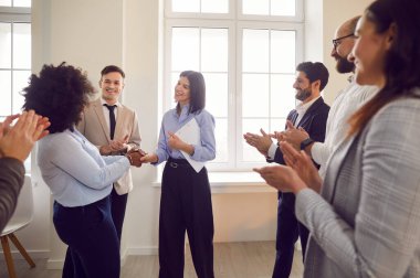 Mutlu gülen çalışanlar işyerinde yeni işçiyi sıcak karşılıyor, arkadaş canlısı takım arkadaşları terfiyle iş arkadaşını kutluyor, başarılı bir proje yarattığı için iş kadınını övüyorlar, ofis tanıma.