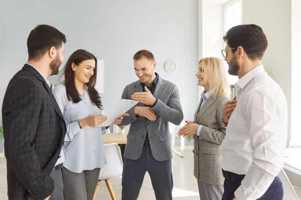 İş yerinde bir grup iş arkadaşı eğleniyor. Ofisteki bir grup insan bir arada durup komik bir şakaya gülüyorlar. İş, işyeri, arkadaşlık kavramı