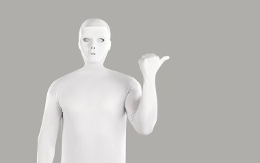 Beyaz tayt giymiş, tanınmayan birinin portresi. Vücut kıyafetli bir adam işaret parmağını yana çevirip gri arka planda izole edilmiş kameraya bakıyor..