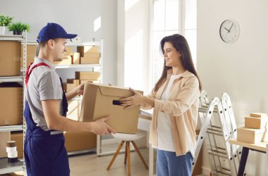 Depoda lojistik ya da dağıtım merkezindeki kadın küçük işletme sahibiyle çalışan teslimat işçisi bir müşterinin siparişini hazırlıyor. Stok envanteri.