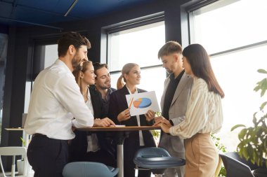 Bir grup kendine güvenen iş adamı modern ofiste bir çember içinde durmuş iş projelerini ya da girişimleri tartışıyorlar. İş arkadaşları ve şirket çalışanları bir toplantıda iş arkadaşlarıyla konuşuyor..