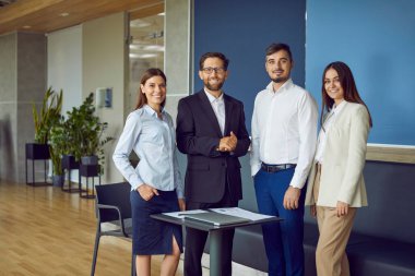 Kendine güvenen iş adamlarının portresi. Takım elbiseli kadın ve erkekler kameraya neşeli bakıyor ve modern ofiste gülümsüyor. Şirket çalışanları ya da bir grup personel toplantı odasında..