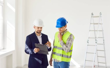 İşadamı ve müteahhit yeni bir ev veya ofiste yenileme veya inşaat projesinin tahminlerini tartışıp hesaplıyorlar. Görüşmede titiz planlama ve bütçe konuları ele alınıyor.