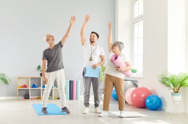 Aktif, neşeli, çekici, formda yaşlı bir kadın, spor kulübü sınıfında antrenör, spor eğitmeni, mutlu, gülümseyen erkek, rehabilitasyon hemşiresi profesyonel refahla çalışan beş kişi.