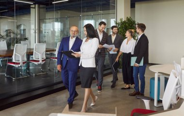 İş adamları modern ofiste tartışarak yürüyor, insanlar dokümanları tartışıyor, şirket stratejilerini tartışıyorlar. Koridorda ya da salonda iş arkadaşlarıyla toplantı