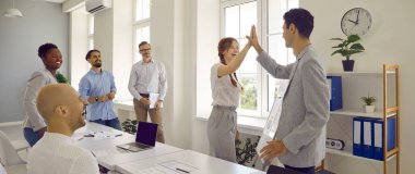 İş başarısı. Mutlu meslektaşlar birlikte çalışmayı başarıyla tamamladıktan sonra birbirlerine beşlik çakarlar. Erkek ve kadın işçiler iş toplantısında birlikte başarılı oldular. Web pankartı.