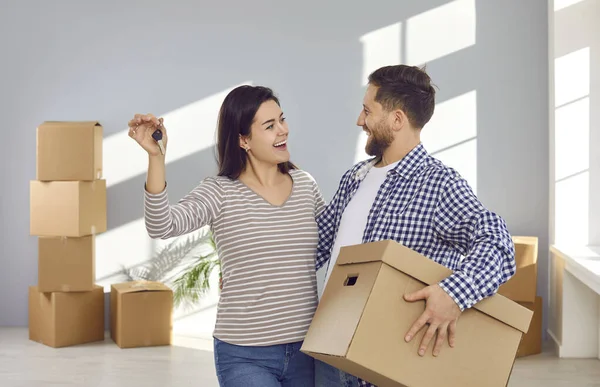 Mutlu genç aile çifti birbirlerine bakıyor, kameranın anahtarlarını gösteriyorlar. Sevgi dolu eşler yeni daireye taşınmayı kutluyor. Taşınma günü, emlak konsepti.