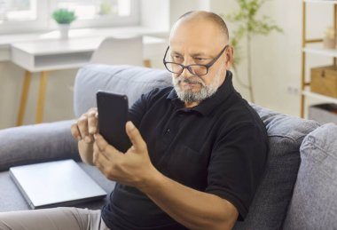 Son sınıf öğrencisi gözlük takıyor, akıllı telefon okuyor. Düzeltilmiş odaklanmayla, parlak bir odada mesajları rahatça okurken görme yeteneği gelişiyor. Kavram: gözlüklü berrak görüş.