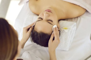 Güzellik uzmanının üst görüşü estetik tıp kliniğindeki kadın müşterilere yüz güzelliği prosedürleri uyguluyor. Kozmetik bilimci ya da dermatolog salonda hastaya estetik yüz bakımı ya da masaj yapar..