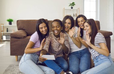 Neşeli yeni nesil z çok ırklı kızlar video konuşmasında cep telefonu ekranı konuşmalarına bakıyorlar. Gülümseyen çok ırklı kız arkadaşların akıllı telefonlarında web kamerası dijital iletişimi vardır..