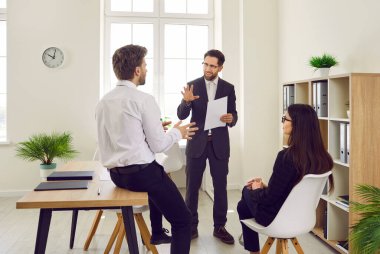 İş adamlarından oluşan bir ekip ofisteki bir iş toplantısında tartışıyorlar. Bir grup erkek ve bir kadın yeni stratejilerini tartışıyor, önerilerde bulunuyor ve birbirlerini dinliyorlar.